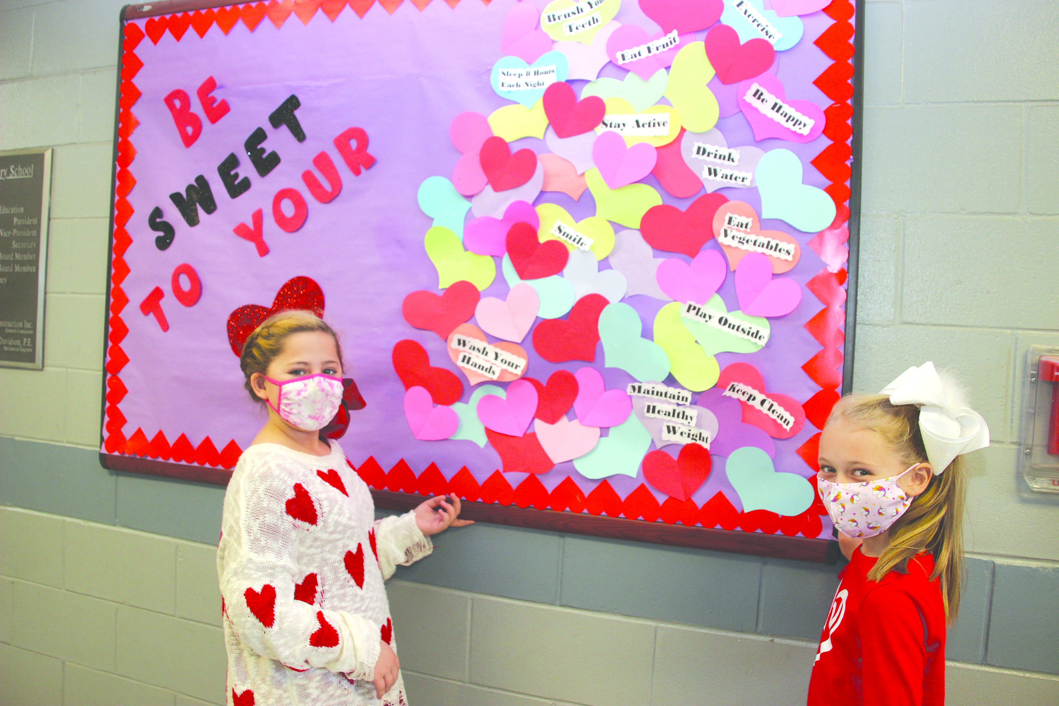 Newton County Elementary third graders Loren Grace Keith and Lanee Beth Parks look over the healthy ways to “Be Sweet to Your Valentine.” Suggestions include washing your hands, being happy, smiling, and brushing your teeth. Submitted photo