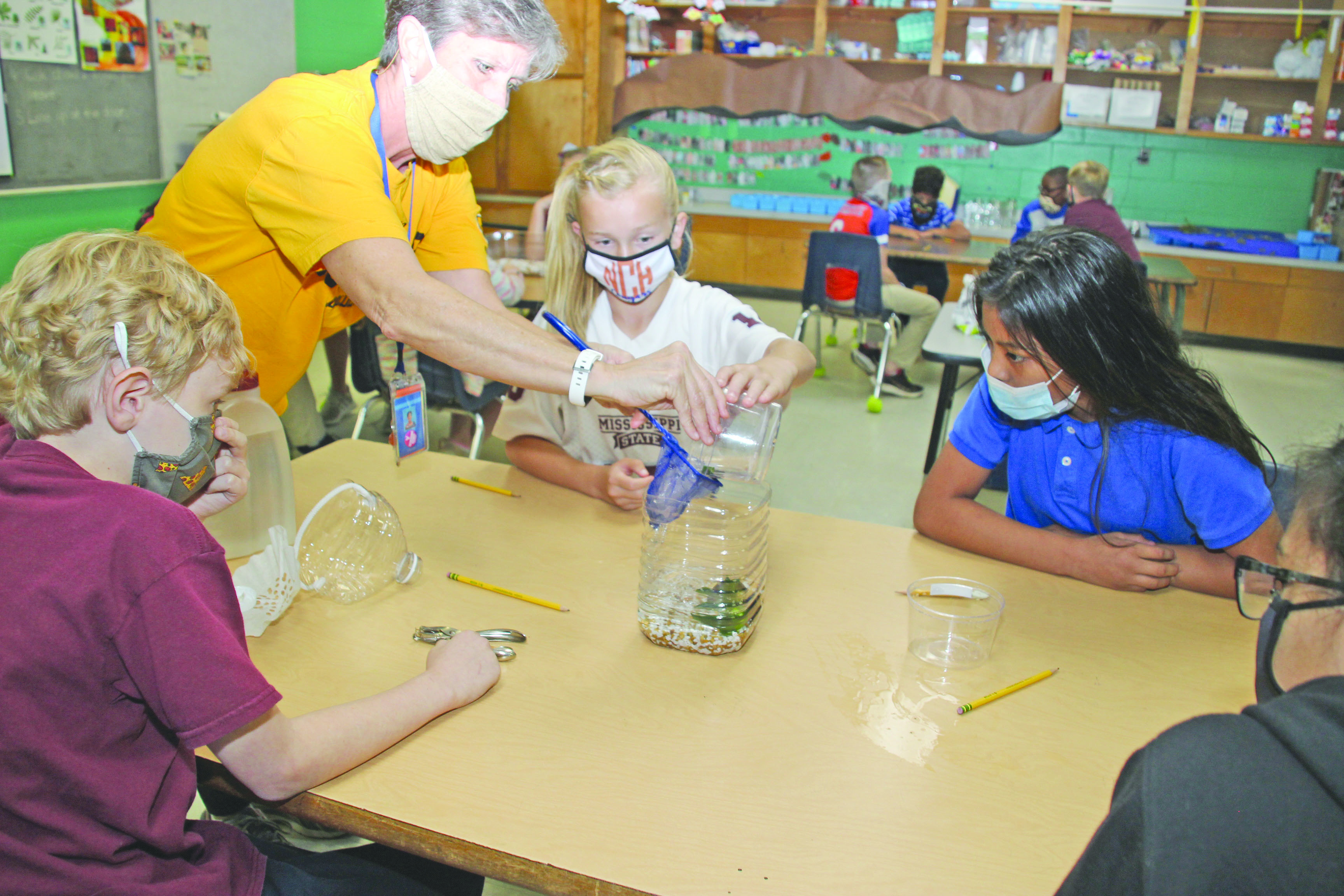 Newton County Elementary Science Instructor Paula Berryhill assists Emma Kate Munn as her class completes its ecosystem this week. Emma Kate’s science partners include, from left, Noah Smith, Kaydison Nickey and Kiara Shoemake.