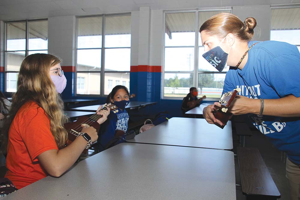 Newton County Middle School seventh grader, McKinley Murphy, perfects the tuning of her ukulele with NCMS Choral Director Emily Massey.