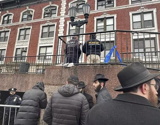 City inspectors and police officers outside the Brooklyn borough, N.Y., headquarters of the Chabad movement, Tuesday, Jan. 9, 2024. On Friday, Jan. 12, The Associated Press reported on stories circulating online incorrectly claiming a secret underground tunnel found connected to the Chabad Lubavitch World Headquarters was used for child sex trafficking or other illicit activities.(AP Photo/Jake Offenhartz)