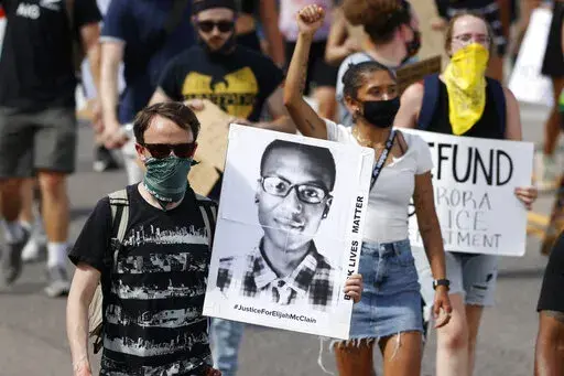 A demonstrator carries an image of Elijah McClain during a rally and march in Aurora, Colo., June 27, 2020. A Colorado judge on Friday, Sept. 16, 2022 responded to a request by a coalition of news organizations to release an amended autopsy report for Elijah McClain, a 23-year-old Black man who died after a 2019 encounter with police, by ruling the report be made public only after new information it contains is redacted. (AP Photo/David Zalubowski, File)