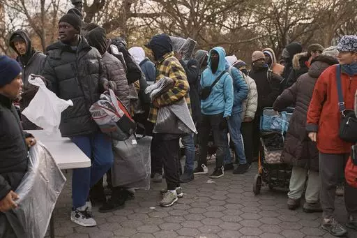 Migrants pick up blankets near a Migrant Assistance Center at St. Brigid Elementary School on Tuesday, Dec. 5, 2023, in New York. Mayor Eric Adam's office on Tuesday, April 9, 2024, said New York City will end its relationship with a medical services company tasked with housing and caring for an influx of international migrants, following scrutiny over the company's lucrative deal with the city and the quality of its humanitarian services. (AP Photo/Andres Kudacki, File)
