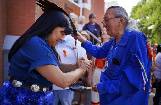 Marlene Poitras participates in a smudging, a ceremonial burning of scented plants for purification and blessing, with church elder Fernie Marty outside of Sacred Heart Church of the First Peoples on Sunday, July 17, 2022, in Edmonton, Alberta. Marty is a survivor of a day school for Indigenous children, which had culturally repressive policies similar to that of residential schools. He has continued practicing his Catholic faith in conjunction with Indigenous ceremonies. (AP Photo/Jessie Wardar