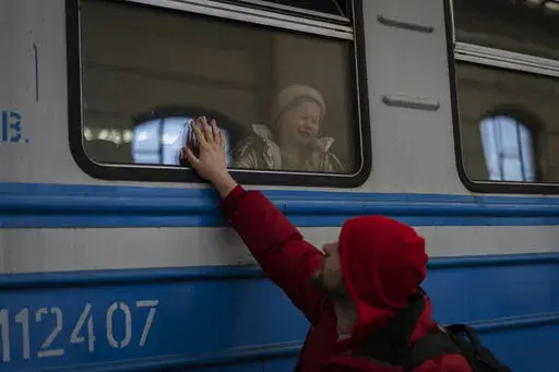 Displaced Ukrainians on a Poland-bound train bid farewell in Lviv, western Ukraine, Tuesday, March 22, 2022. (AP Photo/Bernat Armangue)