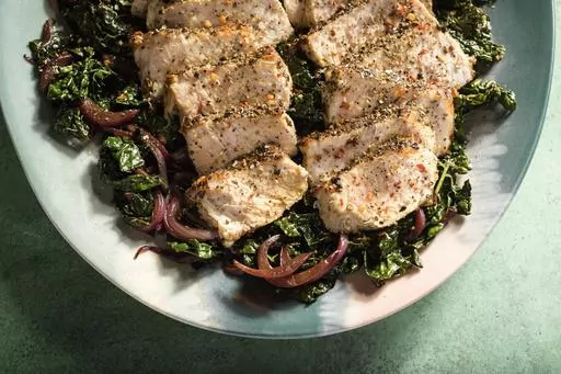 This image released by Milk Street shows a recipe for pork with kale, red wine and toasted garlic. (Milk Street via AP)