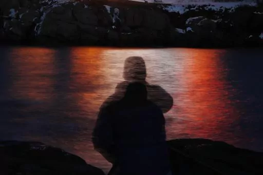 In this photo made with a long exposure, a man is silhouetted against lights reflected in the waters off Cape Neddick in Maine on Dec. 11, 2017. A study published Thursday, Sept. 14, 2023, in the journal Nature Medicine has found that the psychedelic drug MDMA, combined with talk therapy, can reduce symptoms of post-traumatic stress disorder. (AP Photo/Robert F. Bukaty, File)