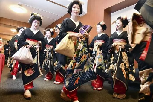 Kimono-clad "geiko" and "maiko" professional entertainers arrive for a ceremony to start this year's business in Kyoto, western Japan, on Jan. 7, 2020. Japan’s ancient capital of Kyoto, long a popular destination for tourists, will be closing off some private-property alleys in its famous geisha district, as complaints grow about misbehaving visitors. (Kyodo News via AP, File)