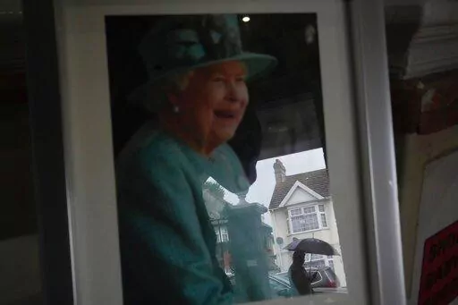 A man is reflected on a photo of Queen Elizabeth II in a Hindu temple, in the district of Southall in London, Tuesday, Sept. 13, 2022. In a church in a West London district known locally as Little India, a book of condolence for Queen Elizabeth II lies open. Five days after the monarch’s passing, few have signed their names. The congregation of 300 is made up largely of the South Asian diaspora, like the majority of the estimated 70,000 people living in the district of Southall, a community tu