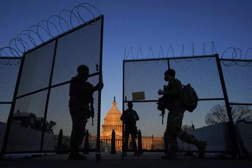 National Guard soldiers open a gate of the razor wire-topped perimeter fence around the Capitol to allow a colleague in at sunrise in Washington, March 8, 2021. (AP Photo/Carolyn Kaster, File)