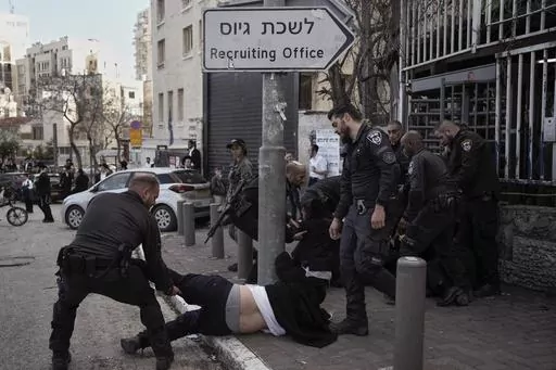 Israeli police officers scuffle with ultra-Orthodox Jewish men during a protest against possible changes to the military draft laws, outside a military recruitment office in Jerusalem, on March 4, 2024. Israel's High Court ruling Thursday to curtail subsidies for ultra-Orthodox men has thrown Prime Minister Benjamin Netanyahu's political future into grave jeopardy. Netanyahu now has until Monday to present the court with a plan to dismantle what the justices called a system that privileges the u