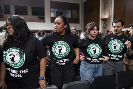 Advocates for a union for Starbucks employees watch as company founder Howard Schultz leaves a hearing after testifying to the Senate Health, Education, Labor and Pensions Committee at the Capitol in Washington on March 29, 2023. Starbucks has been accused of chilling organization by closing unionized stores and firing pro-union workers. (AP Photo/J. Scott Applewhite, File)