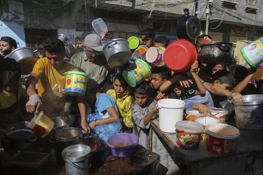 Palestinians crowd together as they wait for food distribution in Rafah, southern Gaza Strip, Nov. 8, 2023. Catastrophic hunger is so dire in two world hotspots that famine is imminent in northern Gaza and approaching in Haiti, with hundreds of thousands of people in both places struggling to avoid starvation, according to international food security experts and aid groups. (AP Photo/Hatem Ali, File)