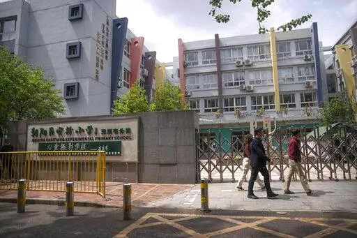 People walk past the gates of a closed primary school in Beijing, Thursday, April 28, 2022. While the U.S. and other countries are dropping restrictions and opening - with some health officials even saying the worst is over - China is keeping its international borders largely shut and closing off entire cities with millions of residents to all but essential travel. For the Chinese capital, however, the political stakes are heightened as the ruling party moves toward a crucial national congress. 