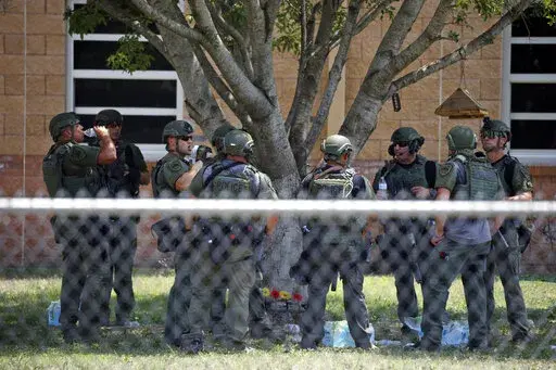 Law enforcement personnel stand outside Robb Elementary School following a shooting, May 24, 2022, in Uvalde, Texas. When the gunman arrived at the school, he hopped its fence and easily entered through an unlocked back door, police said. He holed himself up in a fourth-grade classroom where he killed the children and teachers. (AP Photo/Dario Lopez-Mills, File)