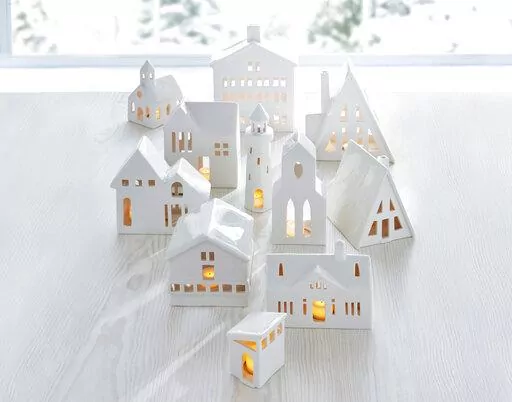 This image provided by Crate & Barrel shows their collection of white ceramic buildings. Crate & Barrel's collection includes alpine homes and hotels as well as midcentury split levels and ranch homes. Add a tealight for a welcoming glow. (Crate & Barrel via AP)