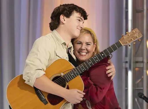 This image released by Disney shows contestant Slater Nalley, left, embracing his English teacher Mrs. Davis during auditions for the singing competition series "American Idol" in Nashville, Tenn. (Eric McCandless/Disney via AP)