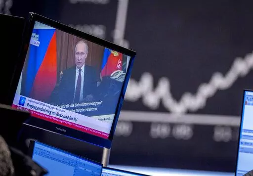Russia's President Vladimir Putin appears on a television screen at the stock market in Frankfurt, Germany, Feb. 25, 2022. Russia is revving up its sophisticated propaganda machine as its military advances in neighboring Ukraine. Analysts who monitor propaganda and disinformation say they've seen a sharp increase in online activity linked to the Russian state in recent weeks. (AP Photo/Michael Probst, File)