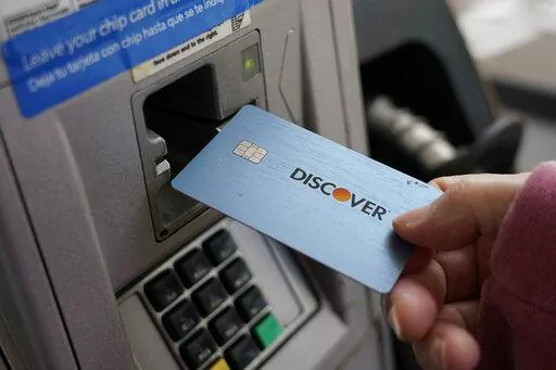 A consumer uses a Discover card in Madison, Miss., Thursday, July 1, 2021.  In 2021,  dedicate a financial account to goods, services and activities that bring you joy. Perhaps this fund would cover monthly massages or weekly smoothies, or it could be used to save up for a vacation.  (AP Photo/Rogelio V. Solis)