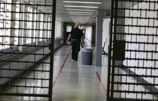 A Rikers Island juvenile detention facility officer walks down a hallway of the jail, Thursday, July 31, 2014, in New York. It's hard to find anyone on board with New York Gov. Kathy Hochul's plan to toughen the state's bail laws, two years after they were retooled to keep people from being jailed because they are poor. The debate over bail in New York has been fierce enough to delay passage of the state's budget. (AP Photo/Julie Jacobson, File)