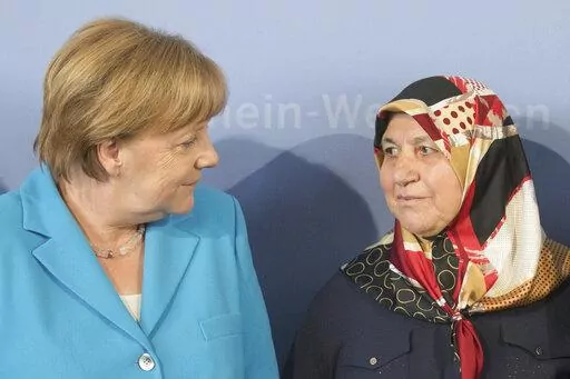 German Chancellor Angela Merkel, left, talks to Mevlude Genc, mother, grandmother and aunt of the victims, in Duesseldorf, western Germany, Tuesday, May 29, 2018 during a commemoration of the 25th anniversary of a firebombing in which five Turks were killed in Solingen. Mevlude Genc, who worked for reconcilition after five members of her family were killed in a racist attack that shook Germany in the early 1990s, has died. (Rolf Vennenbernd/dpa via AP, File)