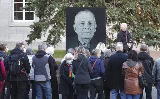 Participants of a memorial service for Buchenwald survivor Boris Romantschenko stand in front of his photo in Weimar, Germany Tuesday, March 22, 2022. Germany’s parliament has paid tribute to Boris Romanchenko, who survived several Nazi concentration camps during World War II but was killed last week during an attack in the Ukrainian city of Kharkiv. He was 96. (Bodo Schackow/dpa via AP)