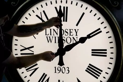 Dan LaMoore adjusts the hands on a Seth Thomas Post Clock at Electric Time Company, Oct. 23, 2020, in Medfield, Mass. Standard time comes to an end in most parts of the United States this weekend. You’ll lose an hour of sleep for one night but gain more daylight in the evening in the months ahead. (AP Photo/Elise Amendola, File)