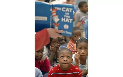 First graders listen as "The Cat in the Hat" is read to them at Chapman Elementary School in Spartanburg, S.C., March 2, 2007, in honor of Dr. Seuss' birthday. Dr. Seuss Enterprises is celebrating the iconic children's author's 120th birthday with a free giveaway of “The Cat in the Hat” to U.S. residents who have a baby born this March 2, 2024. (Tim Kimzey/Spartanburg Herald-Journal via AP, File)