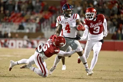 Mississippi running back Quinshon Judkins (4) is tackled by Arkansas defenders Simeon Blair (15) and Dwight McGlothern (3) during the first half of an NCAA college football game Saturday, Nov. 19, 2022, in Fayetteville, Ark. (AP Photo/Michael Woods)