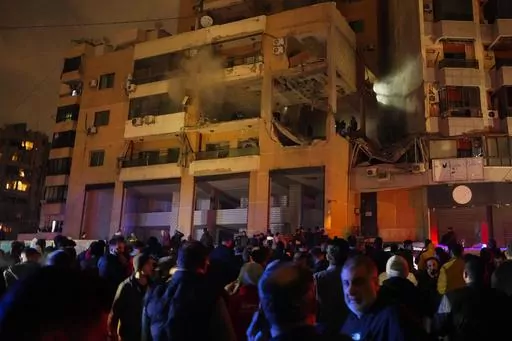 People gather outside a damaged building following a massive explosion in the southern Beirut suburb of Dahiyeh, Lebanon, Tuesday, Jan. 2, 2024. The killing of a top Hamas commander in an apparent Israeli airstrike on a Beirut apartment has given Israel an important symbolic achievement in its 3-month-old war against the Islamic militant group. But history has shown that the benefits of such dramatic operations are often short lived, bringing on further violence and equally formidable replacemen