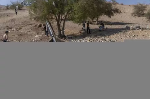 Palestinians cool down in a spring in Auja in the Jordan Valley on Wednesday, Aug.9, 2023. In the occupied West Bank, where Israeli water pipes don’t reach, Palestinians say they can't get enough water to irrigate their farms. By comparison, the neighboring Jewish settlements look like an oasis with swimming pools. (AP Photo/Ohad Zwigenberg)