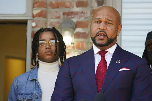 CORRECTS SPELLING OF FIRST NAME TO D’MONTERRIO - FedEx driver D'Monterrio Gibson, left, stands next to his attorney, Carlos Moore, during a news conference in Ridgeland, Miss., Thursday, Feb. 10, 2022. Gibson and his attorneys say the delivery driver was shot at and chased by a white father and son in Brookhaven while making deliveries, and that both suspects have been "undercharged" and call upon the authorities to instead charge the pair with attempted murder and hate crimes. (AP Photo/Rogel