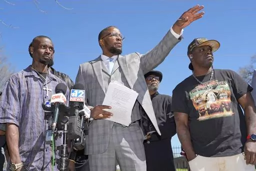 Michael Corey Jenkins, left, and Eddie Terrell Parker, right, stand with lead attorney Malik Shabazz, as they call on a federal judge Monday, March 18, 2024, at a news conference in Jackson, Miss., to impose the harshest possible penalties against six former Mississippi Rankin County law enforcement officers who committed numerous acts of racially motivated, violent torture on them in 2023. The six former law officers pleaded guilty to a number of charges for torturing them. (AP Photo/Rogelio V.