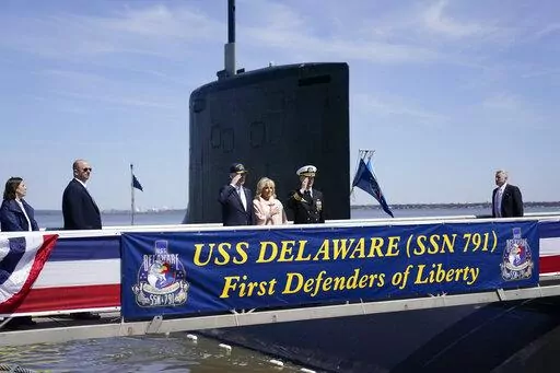 President Joe Biden returns a salute as he stands with first lady Jill Biden and Cmdr. Matthew Horton, Commanding Officer, USS Delaware, before they board the USS Delaware, Virginia-class fast-attack submarine, for a tour at the Port of Wilmington in Wilmington, Del., Saturday, April 2, 2022. (AP Photo/Carolyn Kaster)