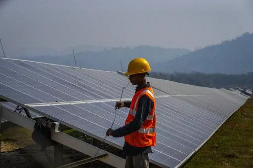 A man works at a solar power plant in Mikir Bamuni village, Nagaon district, northeastern Assam state, India, Feb. 18, 2022. The Indian government took a step toward their climate goals by passing amendments to an energy conservation bill, making it easier to put a price on carbon emissions on polluting industries and encouraging the use of non-fossil fuel sources to generate power across the country. (AP Photo/Anupam Nath, File)