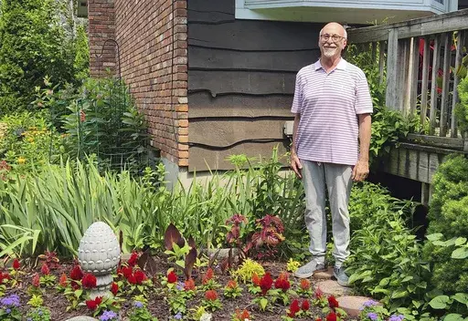 Jeff Kellert stands in his garden at his home in Albany, N.Y. on June 20, 2024. Kellert began volunteering as a tutor and helped with monthly dinners at his synagogue. The experience keeps him active, but just as important, he said, it has led to new friendships and a sense of purpose he never expected in retirement. (Robert Piechota via AP)