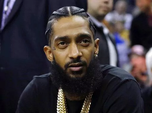 Rapper Nipsey Hussle attends an NBA basketball game between the Golden State Warriors and the Milwaukee Bucks in Oakland, Calif., March 29, 2018. Eric R. Holder Jr., who was convicted last year of fatally shooting Hussle in 2019, is scheduled to be sentenced Wednesday, Feb. 22, 2023, in a Los Angeles courtroom. (AP Photo/Marcio Jose Sanchez, File)