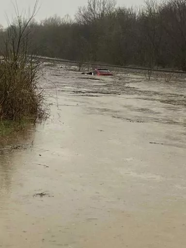 In this photo provided by Layton Hoyer, a red SUV is seen submerged in floodwater on Old Ritchey Road in Granby, Mo., early Friday, March 24, 2023. Hoyer rescued an elderly woman from the car. (Layton Hoyer via AP)