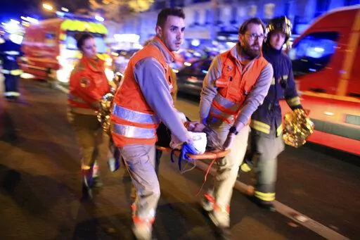 In this Nov. 13, 2015, file photo, a woman is evacuated from the Bataclan concert hall after a shooting in Paris. The last surviving suspect from the 2015 Paris attacks has told a court he felt "ashamed" after failing to detonate his suicide vest on the bloody night of Nov. 13. (AP Photo/Thibault Camus, File)