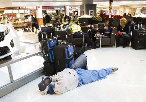 A man sleeps on the terminal floor at Hartfield-Jackson Atlanta International Airport on Dec. 18, 2017, in Atlanta. Transportation Secretary Pete Buttigieg has warned airlines that his department could draft new rules around passenger rights if the carriers don’t give more help to travelers trapped by flight cancellations and delays. The Transportation Department on Friday, Aug. 19, 2022, released a copy of the letters, which it said were sent to CEOs of the major U.S. airlines, their regional