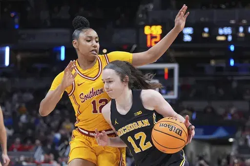 Michigan guard Syla Swords (12) drives on Southern California guard JuJu Watkins (12) during the second half of an NCAA college basketball game in the semifinals of the Big Ten Conference tournament in Indianapolis, Saturday, March 8, 2025. (AP Photo/Michael Conroy)