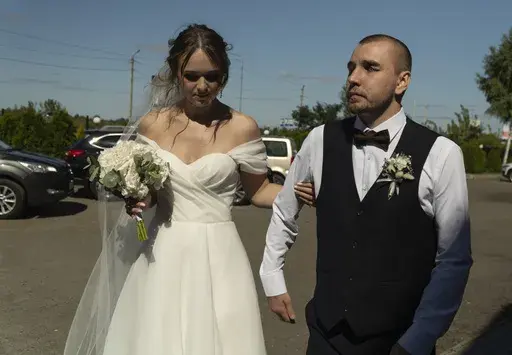 Bride Vladislava Ryabets, left, helps groom Ivan Soroka, right, to walk during their wedding day in Kyiv, Ukraine on Saturday, Sept. 9, 2023. Shrapnel blinded Soroka permanently on Aug. 2, 2022 when Russian mortar fire struck his retreating unit near Bakhmut during the war's longest and bloodiest battle. Despite Soroka's injury the couple has been determined to move forward. (AP Photo/Bela Szandelszky)