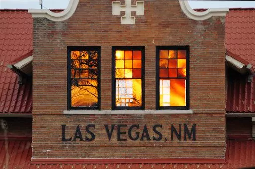 Reddened by wildfire smoke, the sun is seen reflected off windows at the train station in Las Vegas, N.M., on Saturday, May 7, 2022. Area residents have been on and off of evacuation orders of the past month as fires grow and move with intense and unpredictable winds. (AP Photo/Cedar Attanasio)