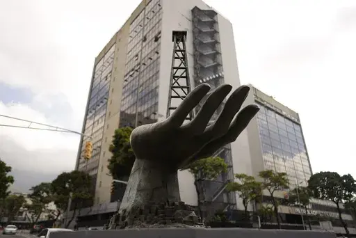 A sculpture of a hand holding an oil drilling rig stands outside the state-run oil company Petroleos de Venezuela S.A. or PDVSA, in Caracas, Venezuela, March 21 2023. (AP Photo/Ariana Cubillos, File)