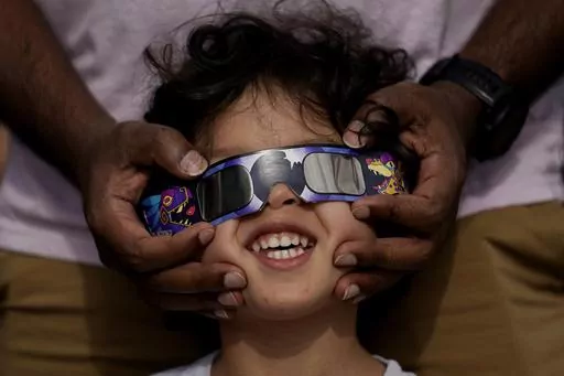 Viewers use special glasses to watch from San Antonio, as the moon moves in front of the sun during an annular solar eclipse, or ring of fire, Oct. 14, 2023. The total solar eclipse on April 8, 2024 may be weeks away but businesses are ready for the celestial event with oodles of special eclipse glasses for sale, along with T-shirts and other souvenirs. (AP Photo/Eric Gay, File)