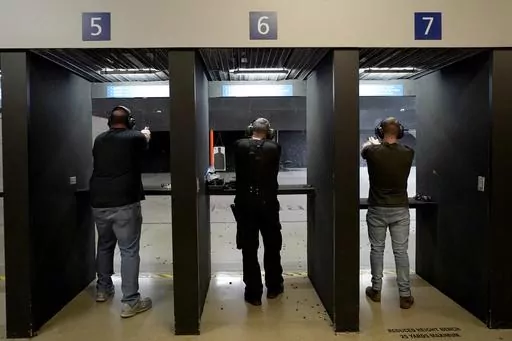 Gun owners fire their pistols at an indoor shooting range during a qualification course to renew their carry concealed handgun permits, July 1, 2022, at the Placer Sporting Club in Roseville, Calif. A California law that bans people from carrying firearms in most public places is taking effect on New Year's Day, even as a court case continues to challenge the law. (AP Photo/Rich Pedroncelli, File)
