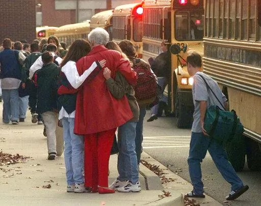 Students arriving at Heath High School in West Paducah, Ky., embrace an unidentified adult on Tuesday, Dec. 2, 1997, after student Michael Carneal opened fire at the school the day before, leaving three students dead and five wounded. In the quarter century that has passed, school shootings have become a depressingly regular occurrence in the U.S. Carneal's upcoming parole hearing in September 2022, raises questions about the appropriate punishment for children who commit heinous crimes. Even if