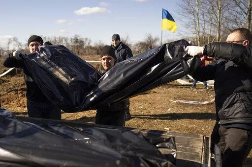 Men carry bags containing three freshly exhumed bodies in a cemetery on the outskirts of Borodyanka, Ukraine, Thursday, March 2, 2023. Nearly a year after towns and villages near Kyiv were retaken from Russian troops who had seized territory as they raced toward Kyiv at the start of their invasion of Ukraine, authorities are still exhuming the bodies of civilians hastily buried in makeshift graves. (AP Photo/Vadim Ghirda)