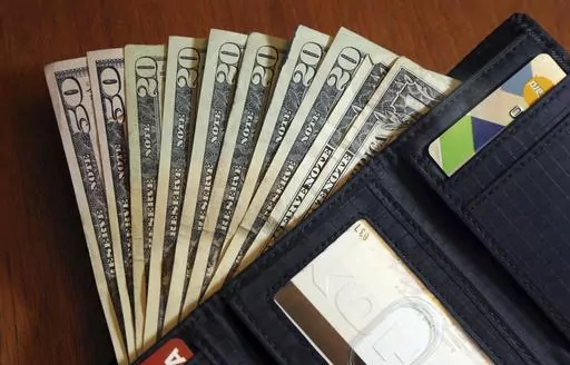 Cash is fanned out from a wallet in North Andover, Mass., June 15, 2018. Too many people cash out their 401(k)s when leaving a job — and part of the problem may be generous employer matches, researchers have found. Large matches can change how employees view their retirement savings, shifting their attitude from viewing a 401(k) as an “untouchable lockbox” to a liquid windfall of sorts. (AP Photo/Elise Amendola, File)