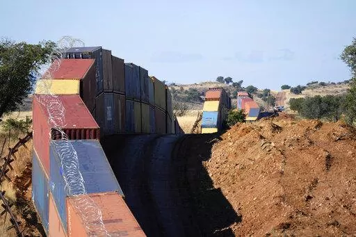 A long row of double-stacked shipping containers provide a new wall between the United States and Mexico in the remote section area of San Rafael Valley, Ariz., Thursday, Dec. 8, 2022. Arizona Gov. Doug Ducey will take down a makeshift wall made of shipping containers at the Mexico border, settling a lawsuit and political tussle with the U.S. government over trespassing on federal lands. (AP Photo/Ross D. Franklin, File)