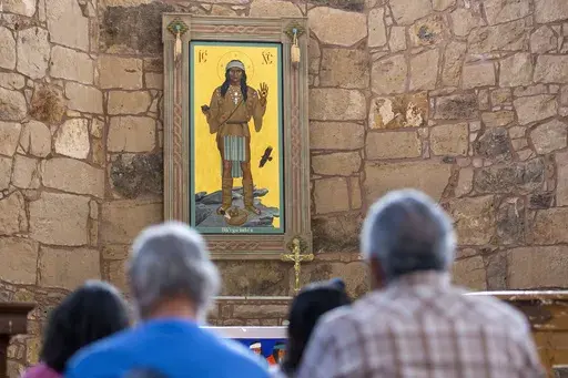 The Apache Christ painting hangs behind the altar of St. Joseph Apache Mission church in Mescalero, New Mexico, Saturday, July 13, 2024. The painting, an icon that depicts Christ as a Mescalero medicine man, was the forefront of a tension-filled episode between the community and the local Diocese when it was removed by the church's then priest when the region was reeling from wildfires. (AP Photo/Andres Leighton)